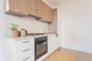 a kitchen with white cabinets and a stove at Ponente Balcony & Garden by Rent All Como in Gravedona