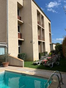 une piscine en face d'un bâtiment dans l'établissement Adonis Arc Hotel Aix, à Aix-en-Provence