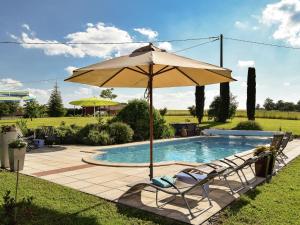 a pool with two chairs and an umbrella at Snug cottage in Saint Eutrope De Born with pool in Saint-Eutrope-de-Born