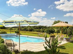una piscina con sombrilla y sillas y una piscina en Snug cottage in Saint Eutrope De Born with pool, en Saint-Eutrope-de-Born