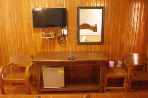 um quarto de madeira com uma mesa e uma televisão na parede em บ้านสวนกุหลาบแก้วรีสอร์ท em Ban Mae Lai