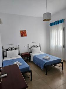 a bedroom with two beds and a table and a table at Hotel Leta in Fira