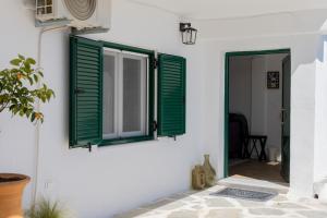 una puerta con persianas verdes en una pared blanca en Villa Luminosa by Corfuescapes, en Spartýlas