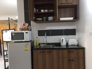 a kitchen with a white refrigerator and a microwave at Cozy roomy condo near Big C and Payap University in Chiang Mai