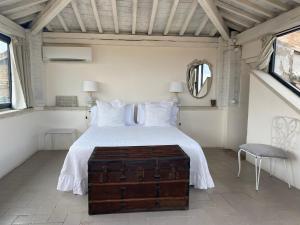a bedroom with a white bed with a wooden trunk at 1550 Residenza d’Epoca in Siena
