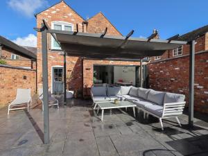 a pergola with couches and a table on a patio at Anglesey House in Nantwich