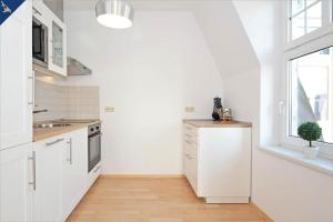 a kitchen with white cabinets and a sink and a window at Apartment Karlskrona in Ahlbeck