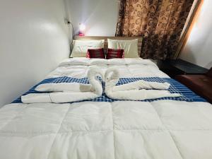 a large white bed with two towels on it at Noot's Bar And Guesthouse in Kanchanaburi