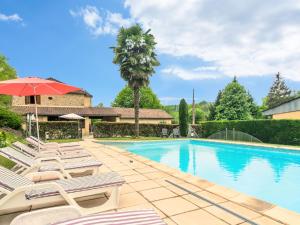 a swimming pool with lounge chairs and a palm tree at Chic Holiday Home in Siorac en P rigord with in Siorac-en-Périgord