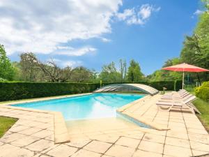 a swimming pool with two lounge chairs and an umbrella at Chic Holiday Home in Siorac en P rigord with in Siorac-en-Périgord