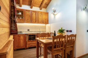 a kitchen with wooden cabinets and a wooden table and chairs at Chalet Camping Faè 5 - Trilocale in Madonna di Campiglio