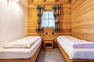two beds in a room with wooden walls and a window at Chalet Camping Faè 5 - Trilocale in Madonna di Campiglio