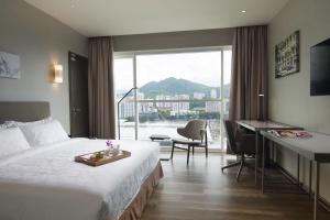 a hotel room with a bed and a desk and a window at Olive Tree Hotel Penang in Bayan Lepas