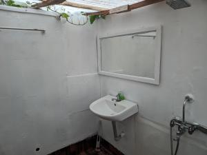 uma casa de banho branca com um lavatório e um espelho em Tides by TB em Canacona