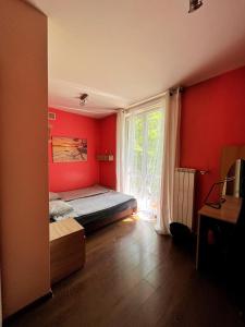 クラクフにあるCosy room Aleja Kijowskaの赤い壁のベッドルーム1室、窓付きのベッド1台が備わります。