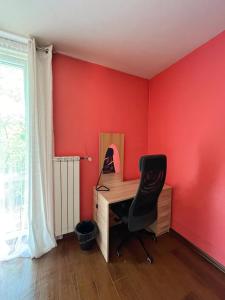 a desk and a chair in a room with red walls at Cosy room Aleja Kijowska in Krakow