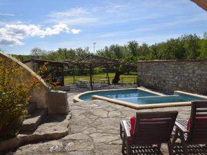 a swimming pool with two chairs and a stone wall at Amazing apartment in Lanas with large garden in Lanas