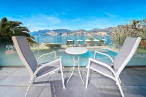 een balkon met een tafel en stoelen en uitzicht op het water bij Hotel Capri in Malcesine