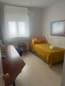 een slaapkamer met een bed met een gele sprei en een raam bij Mara Playa Victoria Ascensor Grupo AC Gestion in Cádiz