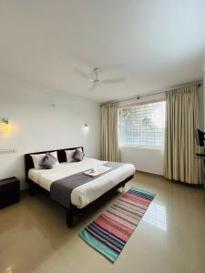 a bedroom with a bed and a window and a rug at Red Stone Villas in Madikeri