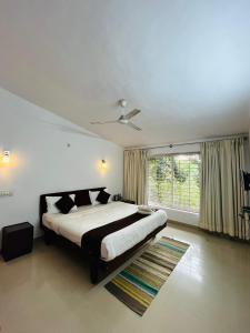 a bedroom with a large bed and a window at Red Stone Villas in Madikeri