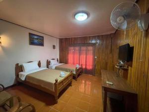a bedroom with two beds and a flat screen tv at บ้านสวนกุหลาบแก้วรีสอร์ท in Ban Mae Lai