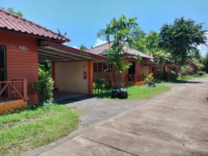 ein rotes Haus mit einem Baum neben einer Straße in der Unterkunft บ้านสวนกุหลาบแก้วรีสอร์ท in Ban Mae Lai