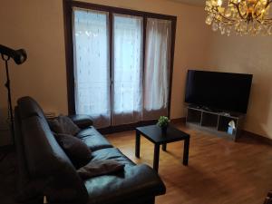 a living room with a couch and a flat screen tv at Gîte l' Odyssée in Espalion