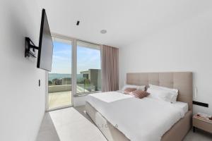 sypialnia z białym łóżkiem i dużym oknem w obiekcie LIOQA Resort w mieście Ugljan