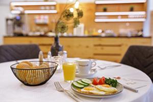 a table with a plate of food and a cup of orange juice at Landgasthof Schmid - Unterkunft & Restaurant in Sitzenberg