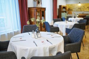 un comedor con mesas y sillas blancas en Landgasthof Schmid - Unterkunft & Restaurant, en Sitzenberg