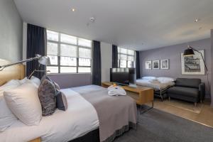 a hotel room with two beds and a desk at Apex City Of London Hotel in London