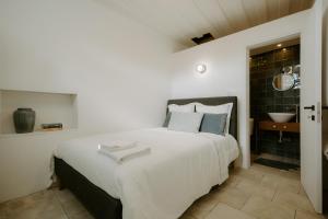 a bedroom with a large white bed and a bathroom at Smaragda's Guest Rooms in Limassol