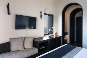a bedroom with a couch and a flat screen tv at Nimbus Santorini in Oia