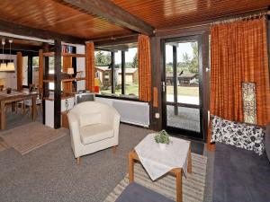 uma sala de estar com uma cadeira e uma mesa em Wooden chalet with terrace near a swimming lake em Waldkirchen