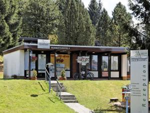 um pequeno edifício num parque com árvores ao fundo em Wooden chalet with terrace near a swimming lake em Waldkirchen