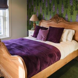 a bedroom with a large wooden bed with purple sheets at The Cleveland Tontine in Northallerton