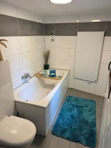 a bathroom with a tub and a toilet and a blue rug at 4711 Suite in Siegburg