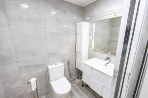 a white bathroom with a toilet and a sink at Vista MarVilla Eira Nova in Porto Covo
