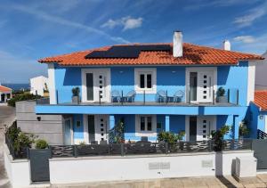 a blue house with chairs on the balcony at Vista MarVilla Eira Nova in Porto Covo