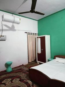 1 dormitorio con 1 cama y ventilador de techo en Gyanbhumi Homestay Ayodhya, en Faizābād
