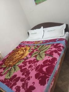 a bed with a colorful blanket and two pillows on it at Royal Queen Residency in Ooty