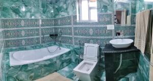 a green tiled bathroom with a tub and a sink at Queens Lakehouse in Srinagar