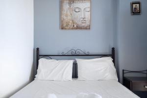 1 cama con almohadas blancas y una foto en la pared en Iguana studio 3, en Preveza