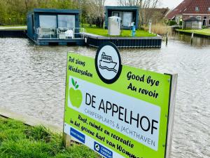 un cartello vicino a un corpo d'acqua con una barca di Uniek overnachten in een Tiny House op de Appelhof a Wommels