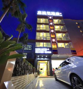 a white car parked in front of a building at Care Hotel Coast Collection in Sanya