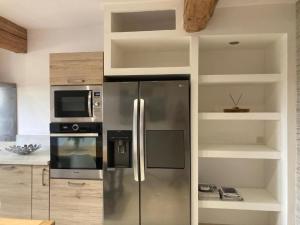 a kitchen with a stainless steel refrigerator and microwave at La porte chamarrée... in Saint-Nicolas-de-la-Grave