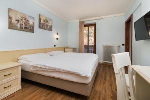 a bedroom with a white bed and a television at Hotel Opinione Dimora Storica in San Lorenzo in Banale