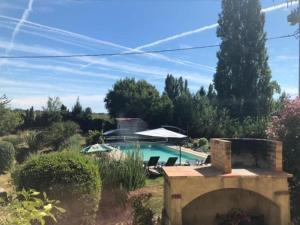 a pool with chairs and an umbrella in a yard at La porte chamarrée... in Saint-Nicolas-de-la-Grave