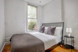 a white bedroom with a large bed with a window at Classic LES 1br w wd nr SoHo NYC-646 in New York